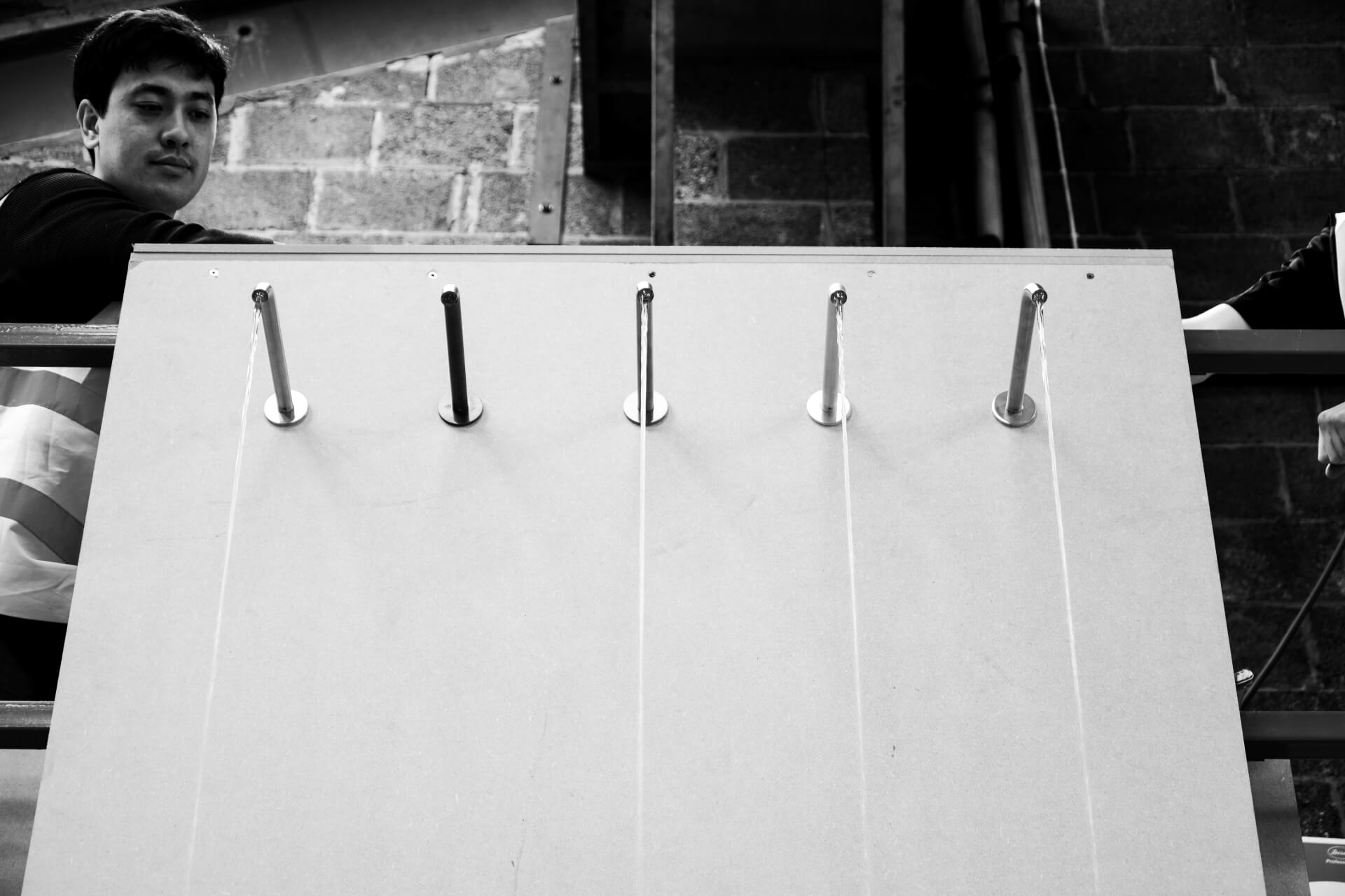 Black and white image of a Splash Lab worker contemplating the four-metre waterfall project featuring 5 capacitive taps